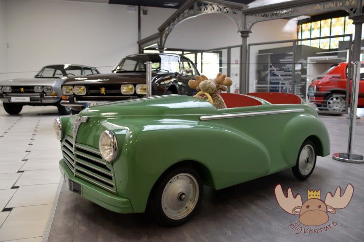 Älgbert in einem Spielzeug Peugeot 203, im Hintergrund Peugeot 504 Coupe - Älgbert in a toy Peugeot 203, in the background Peugeot 504 Coupe